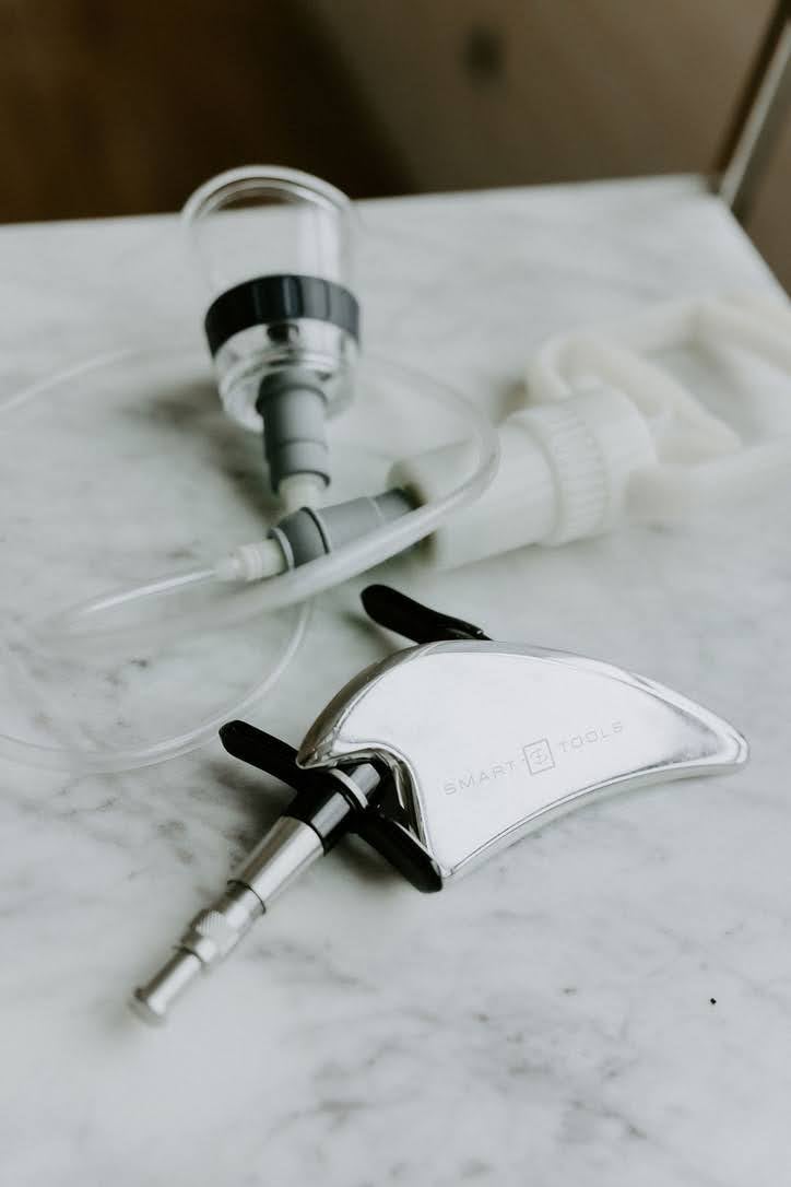 Chiropractic care tools on a marble surface, including a myofascial release instrument and cupping equipment, used for holistic treatment at Redbird Wellness.
