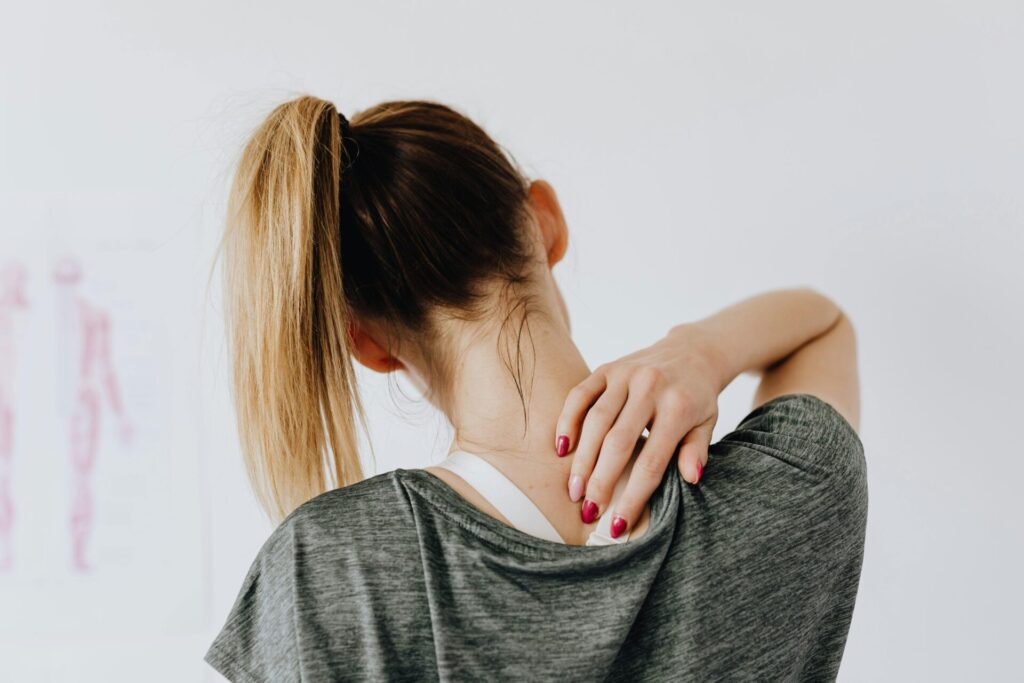 Woman holding her neck and shoulder due to tension, illustrating the need for myofascial release therapy for neck pain.