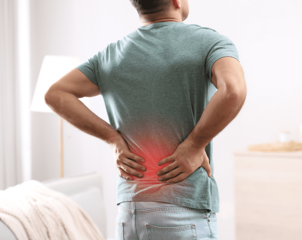Man holding his lower back with highlighted discomfort, illustrating common symptoms of low back pain.