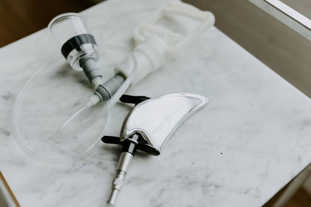 Chiropractic and soft-tissue tools used for conservative shoulder tear treatment, placed on a marble surface at a Hopkins clinic.