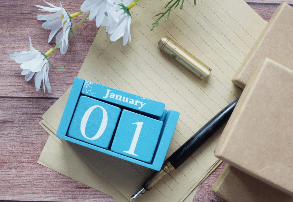 Preparing for the new year with a January 1 calendar, notebook, pen, and wrapped gifts arranged for reflection, planning, and a fresh start.