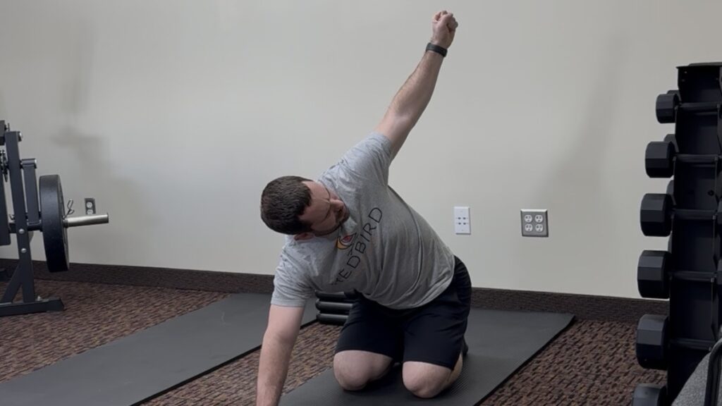 Patient performing a guided side-bending exercise to improve mobility and reduce low back pain.