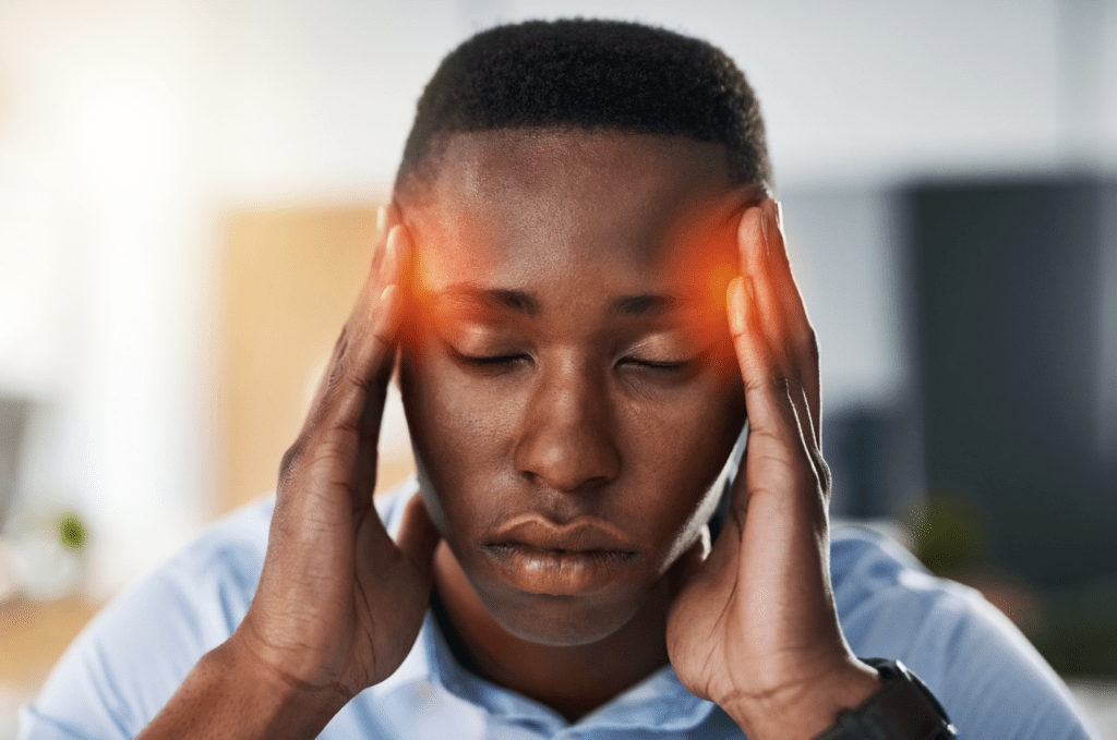 Person pressing temples with highlighted pain areas, representing tension headaches connected to TMJ and cervical dysfunction.