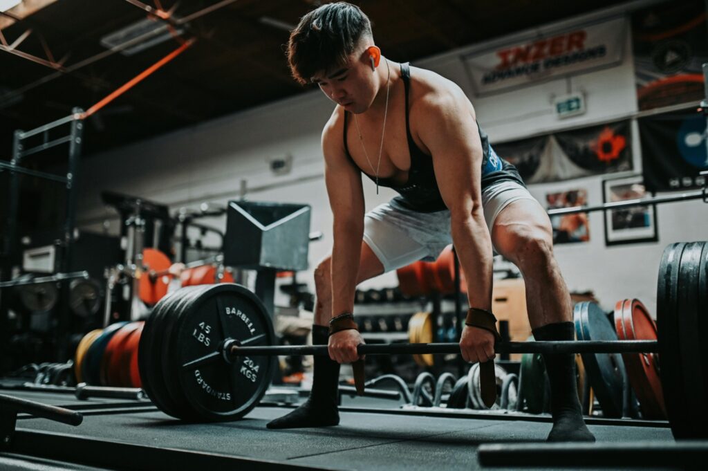 Athlete performing heavy deadlift in gym to build muscle growth through compound strength training and resistance exercise.