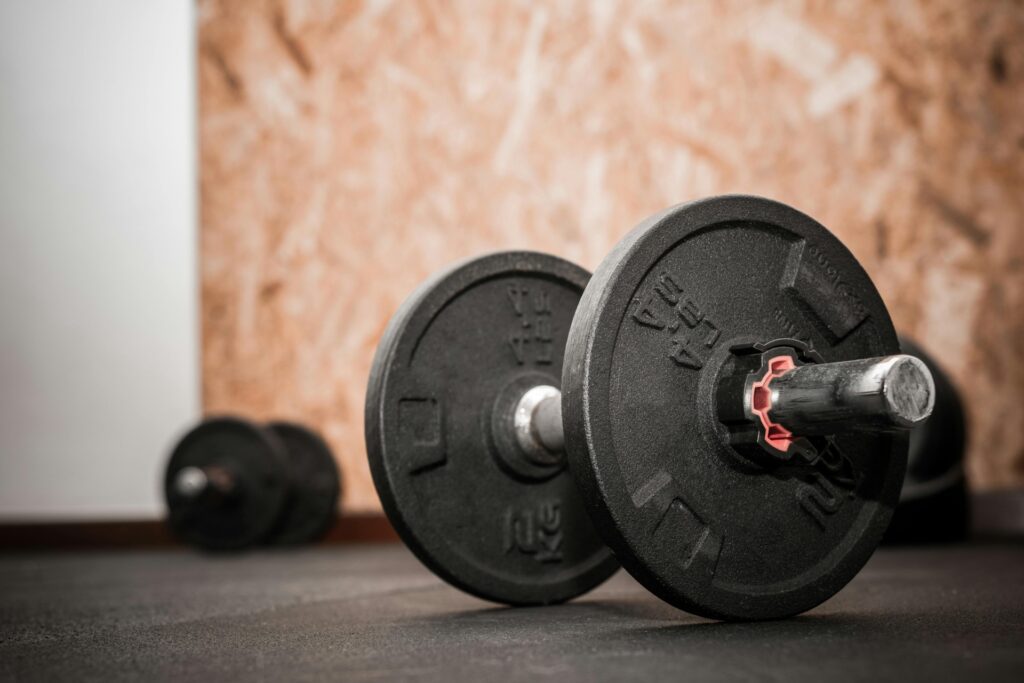 Dumbbells on gym floor representing strength training for muscle growth and progressive overload in a fitness environment.