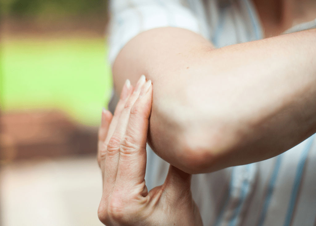 Person holding elbow in pain illustrating tendon irritation and the need for integrated movement to restore function and reduce sensitivity.