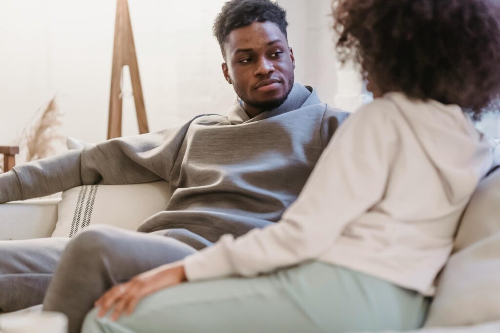 Couple having an open conversation on a couch, representing communication, emotional safety, and healthy relationships.