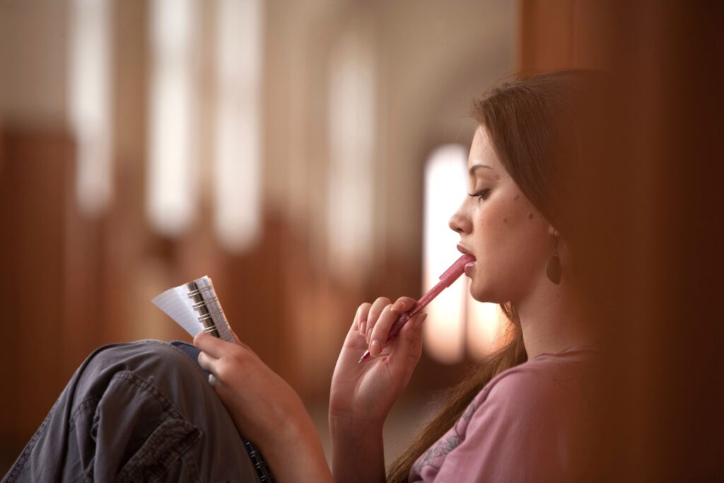 Woman journaling quietly while reflecting on past experiences and processing trauma in a calm, peaceful setting.