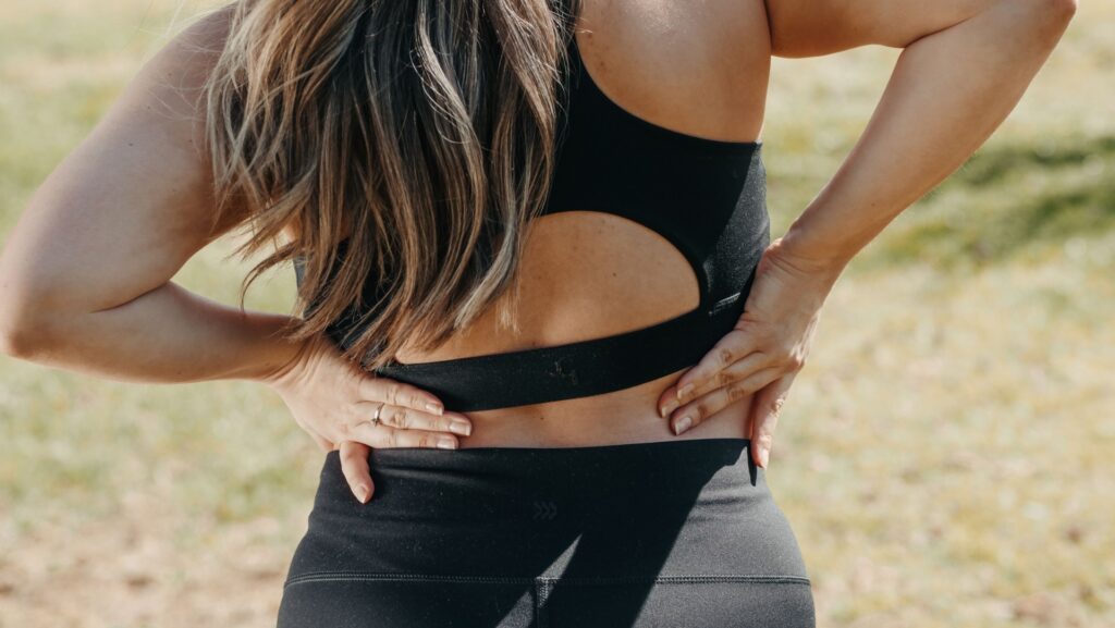 Person holding their lower back while experiencing sciatica pain, highlighting common symptoms of nerve irritation and low back discomfort.
