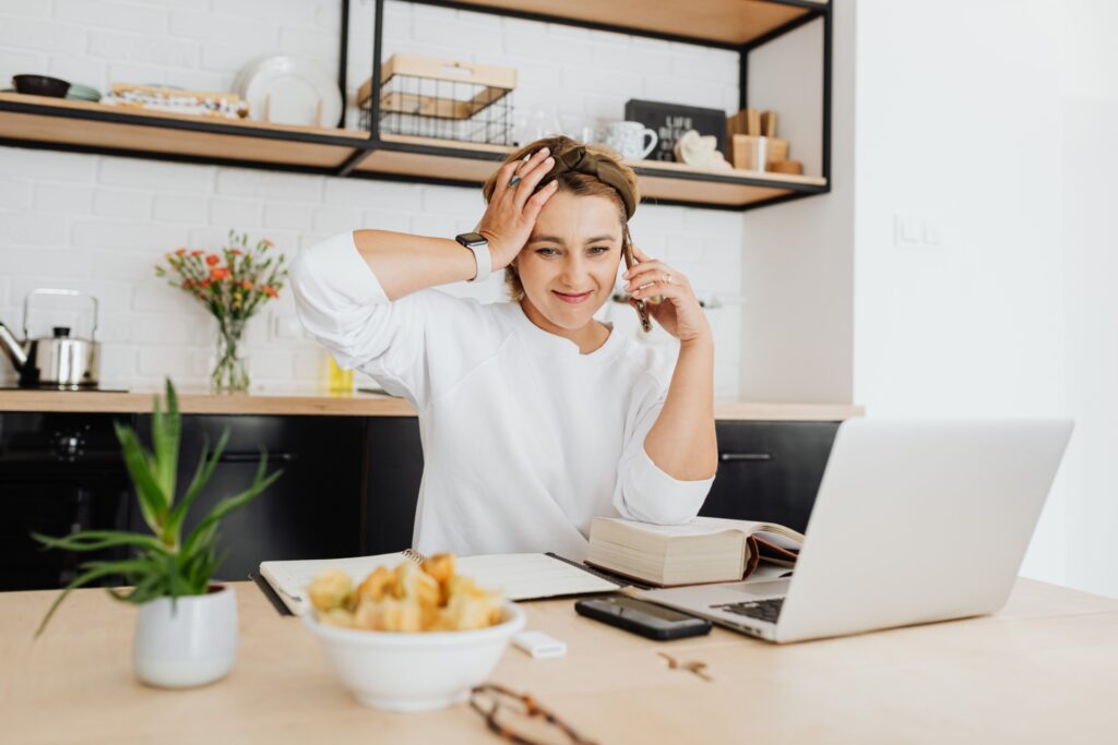 Woman multitasking on the phone while working from home, reflecting the overwhelm and constant productivity of high-functioning anxiety.