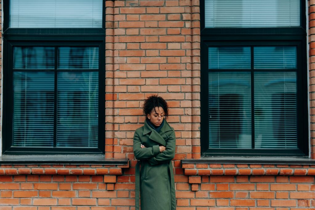 Woman standing alone with her arms crossed, reflecting how understanding what trauma actually is can include chronic emotional experiences.