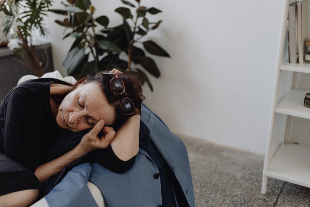 Exhausted woman resting on a chair at home, reflecting the fatigue and emotional depletion associated with burnout and depression.