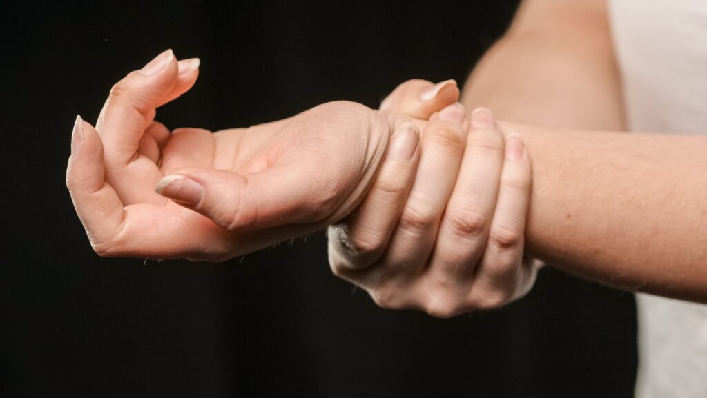 Close-up of a woman holding her wrist, illustrating pain and discomfort associated with carpal tunnel syndrome.